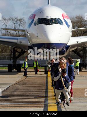 (Da davanti a dietro) Nicola Adams, Gabby Logan, Gary Lineker, Joe Wicks, Iwan Thomas e Alfie Hewett si uniscono ai membri del personale nel tentativo di rompere il Guinness World Record per il più pesante tiro in aereo 100m A350 durante un evento di Sport Relief all'aeroporto di Heathrow a Londra. Foto Stock