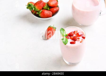 Yogurt alla fragola con frutti di bosco freschi in vetro su sfondo di pietra chiara con spazio di testo libero. Concetto sano di cibo e bevande. Foto Stock