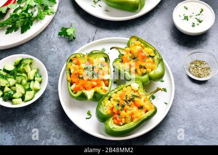 Peperoni verdi ripieni riempiti di mais, carota, cavolfiore su piastra bianca su sfondo di pietra blu. Dieta sana o cibo vegetariano vegano conc Foto Stock