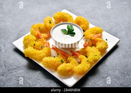 Gamberi biologici fritti con salsa su piatto bianco su fondo di pietra. Vista ravvicinata Foto Stock