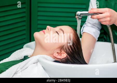 Parrucchiere lavaggio capelli di donna in lavello presso salone di bellezza. Foto Stock