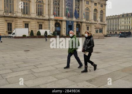 Le persone camminano indossando maschere a Piazza Castello a Torino.l'Italia ha registrato un aumento del 25% dei casi di coronavirus in 24 ore, con infezioni che restano centrate su focolai in due regioni settentrionali, Lombardia e Veneto, 2.502 persone sono state infettate dal romanzo Coronavirus finora (tra queste 79 persone sono morte - principalmente a causa di un precedente e grave quadro clinico compromesso dal virus, 2263 persone sono attualmente positive e 160 persone già recuperate). La diffusione segna la più grande epidemia d’Europa, spingendo il governo italiano a emanare draconiane misure di sicurezza. Foto Stock