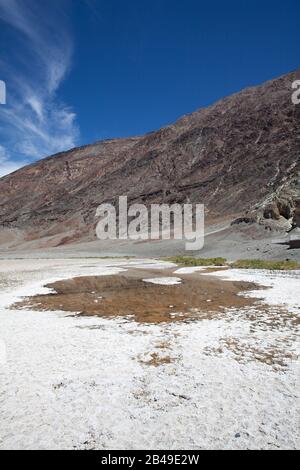 Lago salato nel Parco nazionale Della Valle Della Morte, località conosciuta anche come Badwater Basin, con la montagna riflessa in un pozza d'acqua Foto Stock