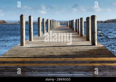 Passerella sopra lago allagato choppy acqua forte venti acqua ruvida a destra mostra bagnato riparato legno colori inverno tempesta 2020 Foto Stock