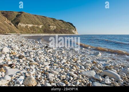 Paesaggio scena costiera di grande spiaggia di ghiaia pietra con calchi scogliere che cadono in mare Foto Stock