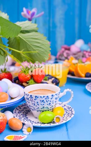 Colazione di Pasqua. Caffè espresso fresco aromatico, succo d'arancia, uova di pasqua, muesli, su sfondo blu di legno. Spazio di copia Foto Stock