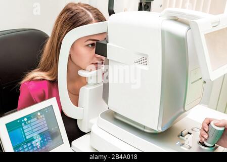 Bella donna che ha un esame obiettivo con rifrattatore automatico cheratometro Foto Stock