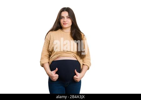 Madre del futuro positiva che fa il gesto dei pollici-in su isolato su sfondo bianco come concetto sano di gravidanza Foto Stock