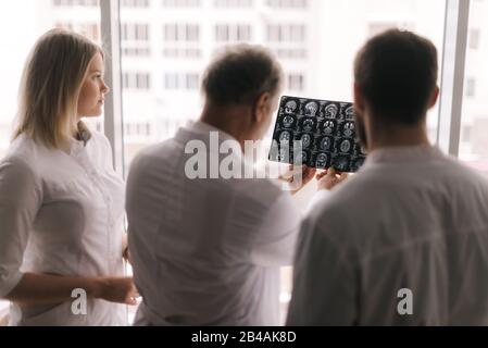 Il team di esperti medici discute i risultati di una scansione RM della testa del paziente Foto Stock