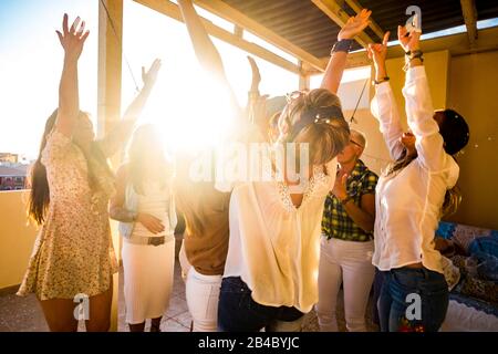 Attivo gruppo felice di giovani liberi caucasici donna celebrare e ballare tutti insieme con l'amicizia - tramonto in retroilluminazione per partito a casa concetto - felicità per il gruppo Foto Stock