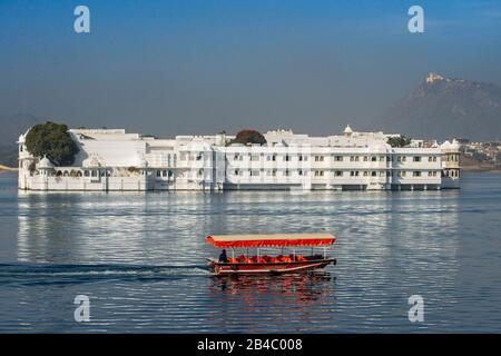 Barca che attraversa il Lake Palace Hotel Jag Niwas nel mezzo del lago Pichola Udaipur Rajasthan India. Questa è una delle escursioni del treno di lusso Foto Stock