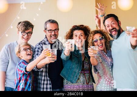 Gruppo di persone caucasiche uomini e donne di età diversa da bambini a adolescenti a adulti godere e celenrate insieme tostare con occhiali e avere un sacco di divertimento per l'amicizia Foto Stock