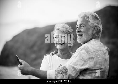 Bel ritratto romantico di senior felice coppia sorriso e abbraccio eachother con amore - per sempre insieme concetto e attivo anziani felice stile di vita - bianco chiaro sfondo e la gente sorridente Foto Stock