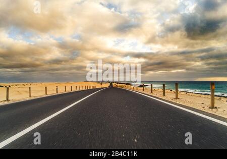 Strada lunga per il trasporto di auto da viaggio concetto con deserto e spiaggia sul lato - acqua di mare e cielo nuvoloso bello in background - effetto movimento Foto Stock