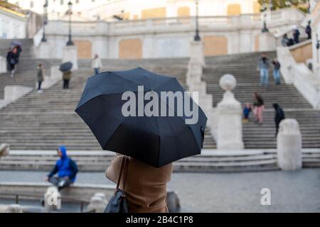 Roma, Italia - 04 Marzo 2020: Donna con ombrello in Piazza di Spagna, in una giornata cupa, che si trova al riparo dalla pioggia. Foto Stock