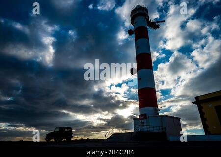 Bellissimo tramonto cielo con nuvole e faro sulla linea costiera - fuoristrada avventura veicolo parcheggiata lì. Concetto di viaggio selvaggio trafvel alternativa vacanza o esplorare il mondo - natura all'aperto scenico luogo Foto Stock