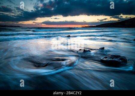 Tramonto selvaggio sulla spiaggia nella stagione invernale. Paesaggio artistico con sole e acqua di mare. Splendido concetto di viaggio e avventura alternativa vacanza. Colori e sfondo con acqua Foto Stock