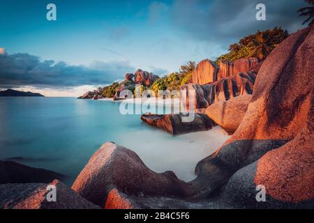 Unica forma di massi di granito e un tramonto spettacolare ad Anse Source d'Argent beach, La Digue Island, Seychelles. Lunga esposizione. Foto Stock