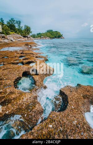 Costa frastagliata di Paradise beach con rocce granitiche e blu acqua cristallina su una costa irregolare di Anse Bazarca, Seychelles. Foto Stock