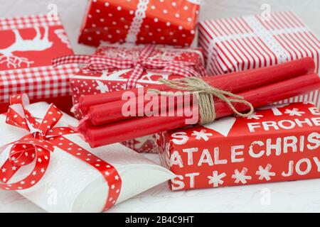 Pacchetto di candele rosse di Natale su molte scatole regalo avvolte in carta bianca rossa Foto Stock