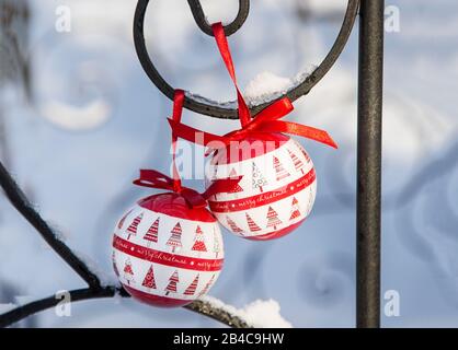 Winterly scenario di Natale con ornamenti palla rosso e bianco appeso da recinzione in ferro nella neve Foto Stock