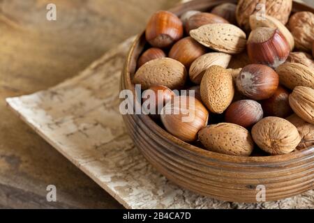 selezione di dadi in vecchio recipiente di legno su sfondo di legno Foto Stock