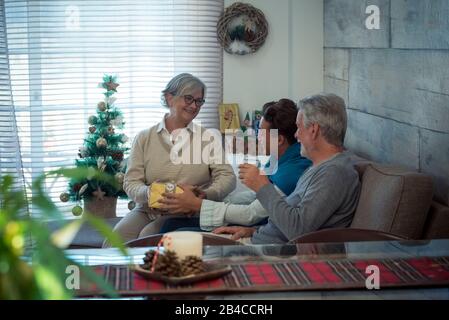 Famiglia con generazioni miste da giovani a anziani celebrare natale insieme a casa con felicità e amore - nonni e nipote seduti sul divano con doni e regali Foto Stock