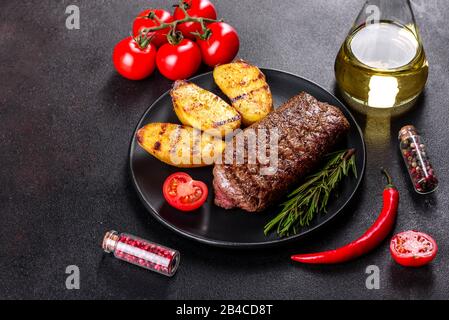 Bistecca Ribeye con patate, cipolle e pomodori ciliegini. Bistecca succosa con burro aromatizzato Foto Stock
