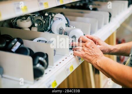 hardware mall people concept - primo piano di mani prendere una ruota dal ripiano del supermercato negozio o il muro con un sacco di ruote - un anziano vuole creare qualcosa Foto Stock