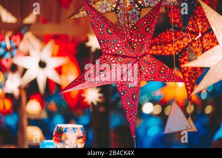 Stelle di colore rosso illuminate con luce sull'albero di Natale al mercatino di Natale ad Amburgo, Germania. Foto Stock