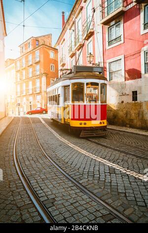 Vintage turistico tram rosso in una strada di Lisbona sul pomeriggio soleggiato, strade strette, ciottoli winding road, vacanza a Lisbona Foto Stock