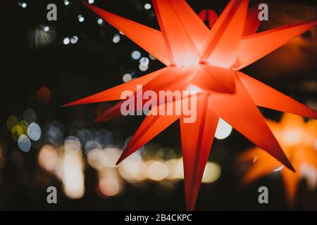 Stelle di colore rosso illuminate con luce sull'albero di Natale al mercatino di Natale ad Amburgo, Germania. Foto Stock