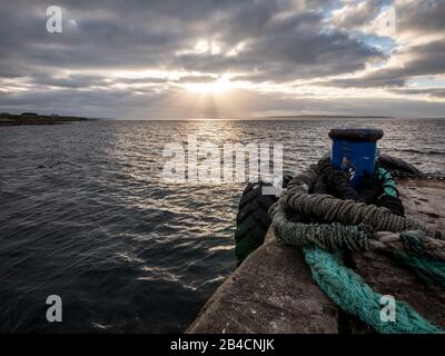 Crepuscolo e le Isole Orcadi. Una vista a nord dal porto di John o'Groats verso Stroma e le Orkneys con luce del sole che si infrange attraverso la copertura della nuvola. Foto Stock