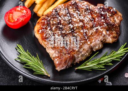 Bistecca Ribeye con patate, cipolle e pomodori ciliegini. Bistecca succosa con burro aromatizzato Foto Stock