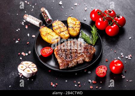 Bistecca Ribeye con patate, cipolle e pomodori ciliegini. Bistecca succosa con burro aromatizzato Foto Stock