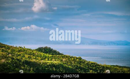 Bellissima vista serale di San Agung Vulcano a Bali dall'Isola di Nusa Penida. Parzialmente Coperto Da Nuvole. Indonesia. Foto Stock