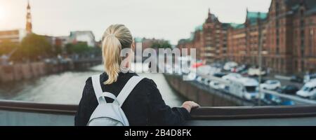 Vista posteriore di una donna con un paesaggio urbano sfocato di Amburgo Foto Stock