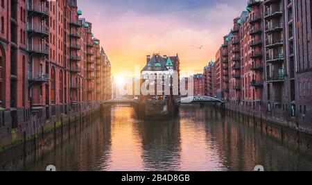 Vecchio porto di Amburgo, Germania, Europa, storico magazzino quartiere con palazzo fossato alla luce dorata del tramonto Foto Stock