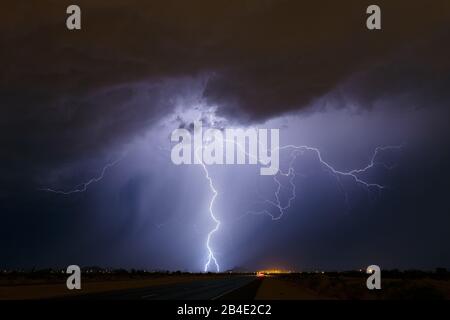 Un fulmine luminoso da nuvola a terra colpisce vicino a una sottostazione elettrica durante una tempesta estiva a Phoenix, Arizona Foto Stock