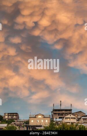 Armenia, Yerevan, drammatica sky e case di collina, crepuscolo Foto Stock