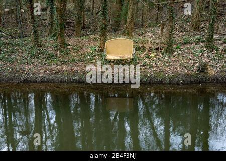 Banco vecchio disposto sulla banca di un ruscello. Foto Stock