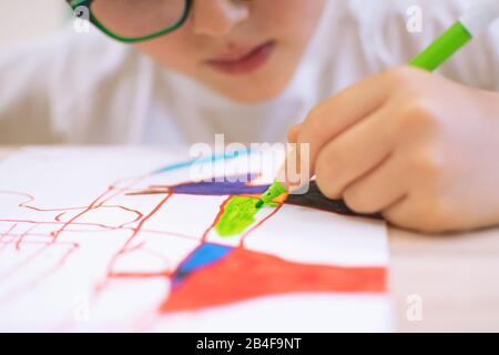 Bambino disegno forme astratte su una carta su colori vibranti. Introduzione della forma astratta attraverso l'ombra di oggetti nella classe di educazione artistica a scuola Foto Stock