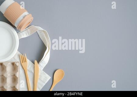 Zero rifiuti di plastica libera con posate di legno, tazza di caffè di bambù, scatola d'uovo, borsa di alimentari su sfondo grigio. Vista dall'alto con spazio di copia Foto Stock