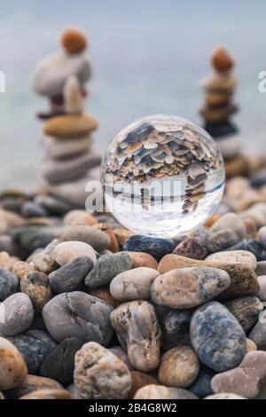 Pila di ciottoli riflessi in una palla di cristallo, spiaggia di Baska, isola di Krk, Kvarner Bay, Primorje-Gorski Kotar County, Croazia Foto Stock