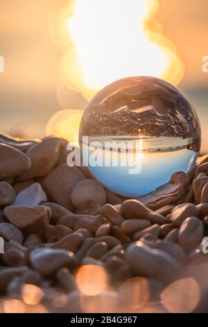 Palla di cristallo sulla spiaggia di ciottoli di MoÅ¡Ä‡eniÄka Draga all'alba, Primorje-Gorski Kotar County, Croazia Foto Stock