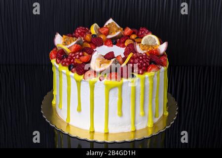 Deliziosa torta gialla di frutta, per il compleanno. Su uno sfondo scuro. Foto Stock