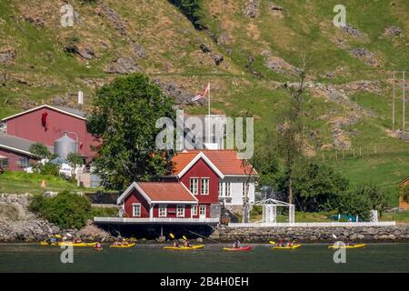 Turisti in kayak gialli su fiordo, Flåm, Gudvangen, muro di pietra, paesaggio di montagna, case di legno rosso, Bakka, Sogn og Fjordane, Norvegia, Scandinavia, Europa Foto Stock