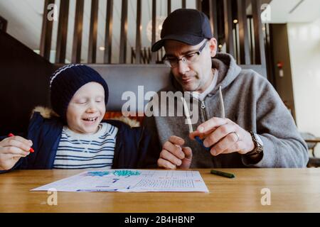 Padre e figlio che colorano in stand ristorante in attesa di cibo Foto Stock
