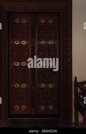 Destinazione Tanzania, Isola di Zanzibar: Impressioni da Stone Town, il più antico distretto di Zanzibar, la capitale dello stato tanzaniano di Zanzibar. Porta di legno in un hotel. Foto Stock