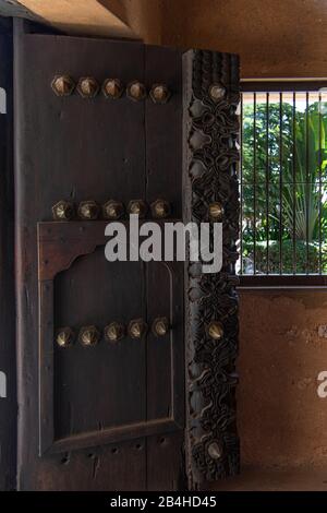 Destinazione Tanzania, Isola di Zanzibar: Impressioni da Stone Town, il più antico distretto di Zanzibar, la capitale dello stato tanzaniano di Zanzibar. Porta di legno nell'area d'ingresso del centro culturale 'Altes Fort' Foto Stock